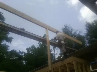 Carpenter setting a ridge beam over a new addition frame — Ice Dam Removal by Roofing Brothers in Malo