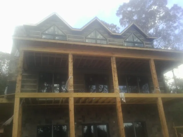 Dormers and porch framing on a large log home under construction — Roof Coating work by our crew in Malo