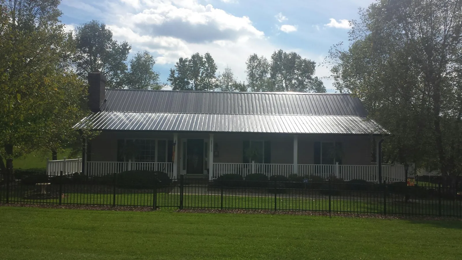 Gray metal roof on a brick ranch with a full width front porch — Gutter Guard Installation work by our crew in Malo