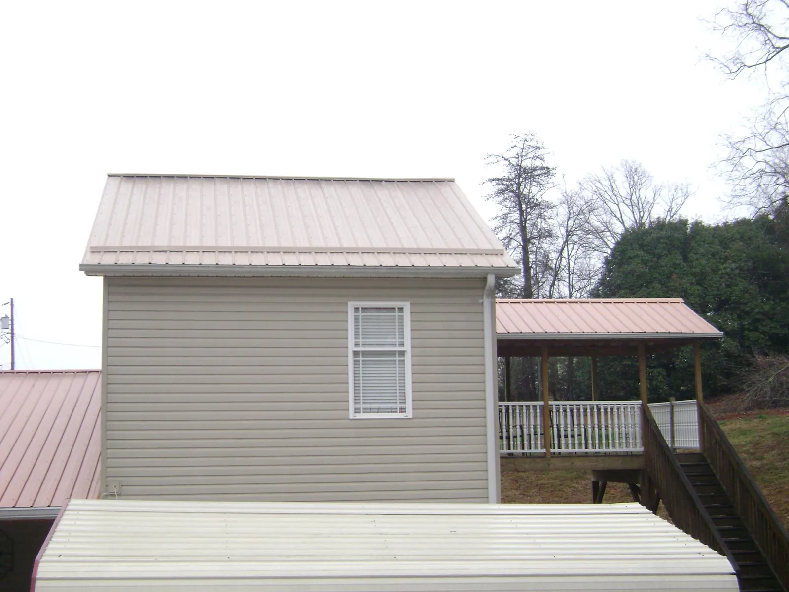 Tan metal roofs on a two story addition and attached porch, from a Roof Replacement job in Malo