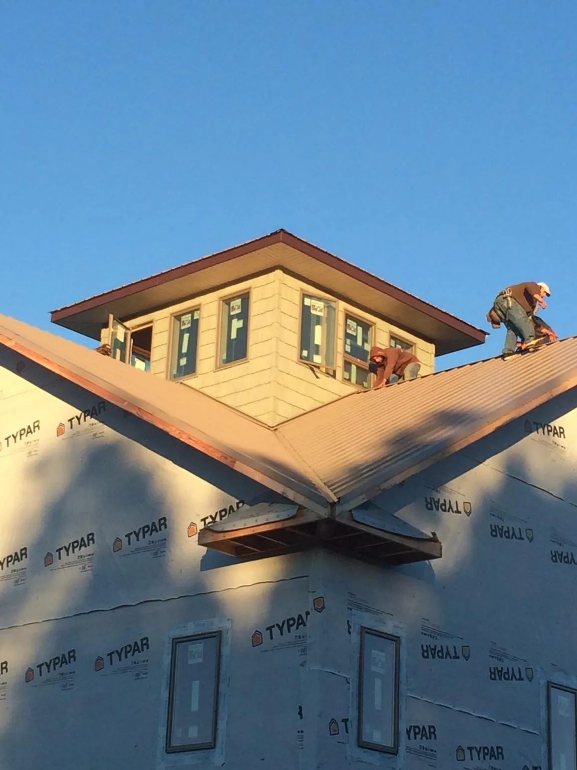 Roofers working around a rooftop cupola on a new metal roof at sunset — Roof Waterproofing in Malo by Roofing Brothers